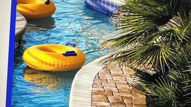 A swimming pool with a tiled edge, a brick pattern, and yellow floating rings. - Cozy condo with WiFi and AC in amazing North Myrtle Beach. (North Myrtle Beach)