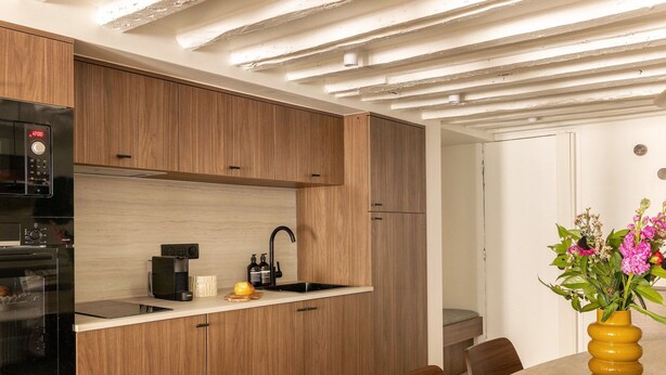 A modern kitchen with wooden cabinets, a built-in oven, and a coffee maker.