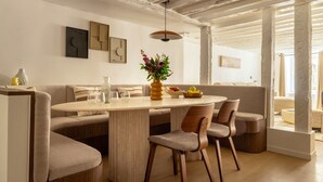 Een moderne eetruimte met een ronde tafel, comfortabele zittingen en een bloemenvaas.