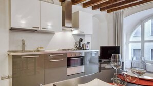 A modern kitchen with stainless steel appliances, a dining area with a table set for two, and a large window providing natural light. - DUOMO 10min - Lovely flat in the center (Milano)