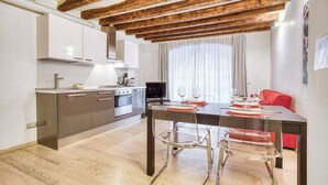 A modern kitchen with wooden beams, stainless steel appliances, and a dining area with a table set for four. - DUOMO 10min - Lovely flat in the center (Milano)