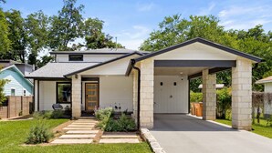 Une maison moderne de plain-pied, dotée d’un garage fermé, d’un porche et d’une pelouse bien entretenue.