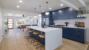 Une cuisine moderne dotée d’un îlot central, de tabourets de bar et d’un coin café.