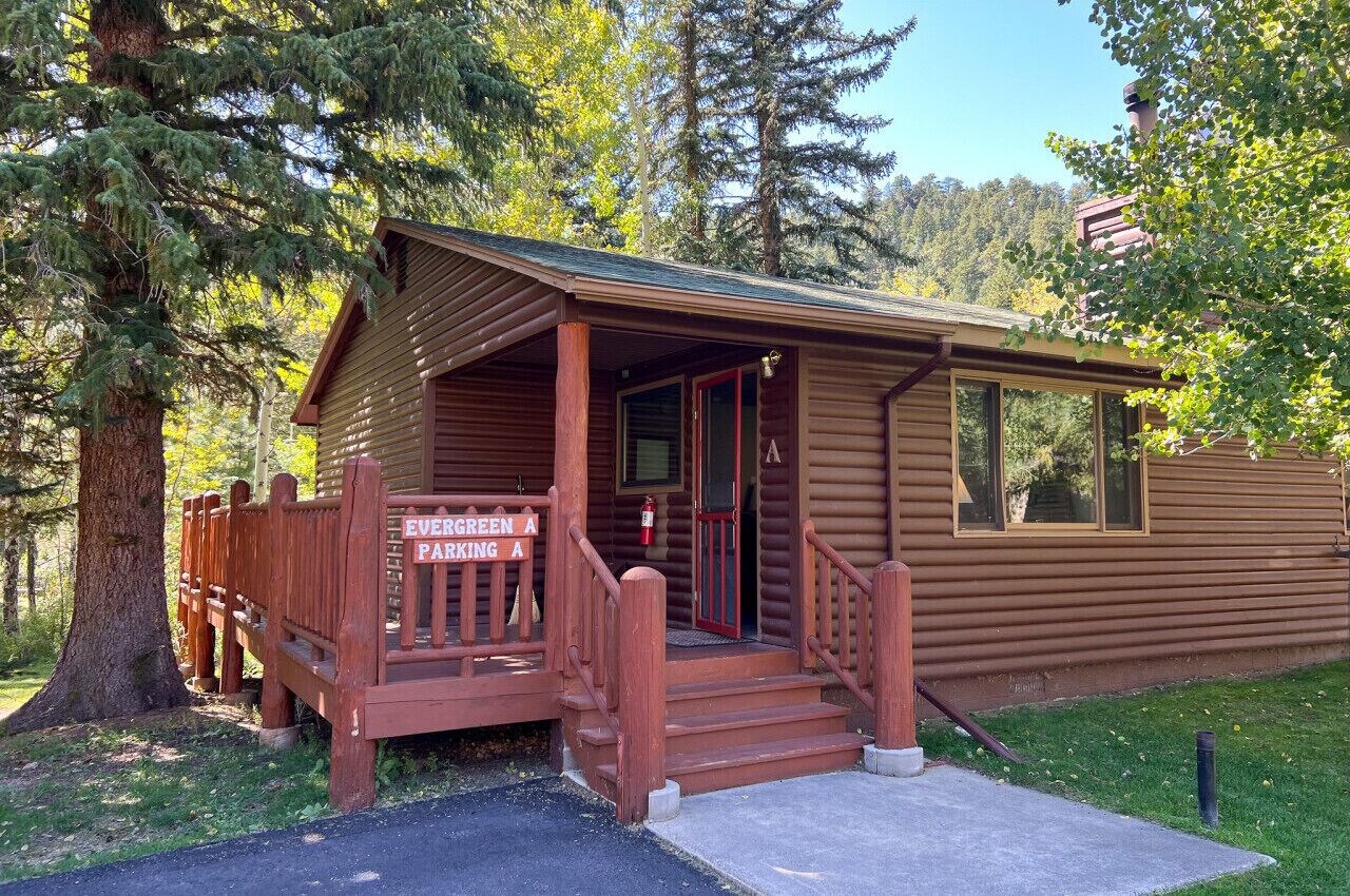 Une petite cabane en bois avec un porche et une pancarte sur laquelle on peut lire : « EVERGREEN A, parking ».