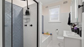 A modern bathroom with a glass shower enclosure, a white sink, and a toilet.