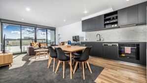A modern kitchen with a dining area, large windows, and a city view.