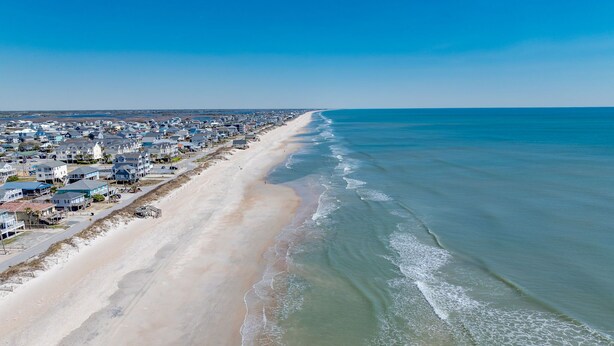 An aerial view of a coastal town with a long beachfront, houses, and a clear sky. - 2 Kitchens, 2 Living Rooms, Sleeps 10 (Surf City)