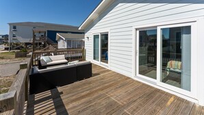 A modern house with a wooden deck, a covered outdoor seating area, and large sliding glass doors. - 2 Kitchens, 2 Living Rooms, Sleeps 10 (Surf City)