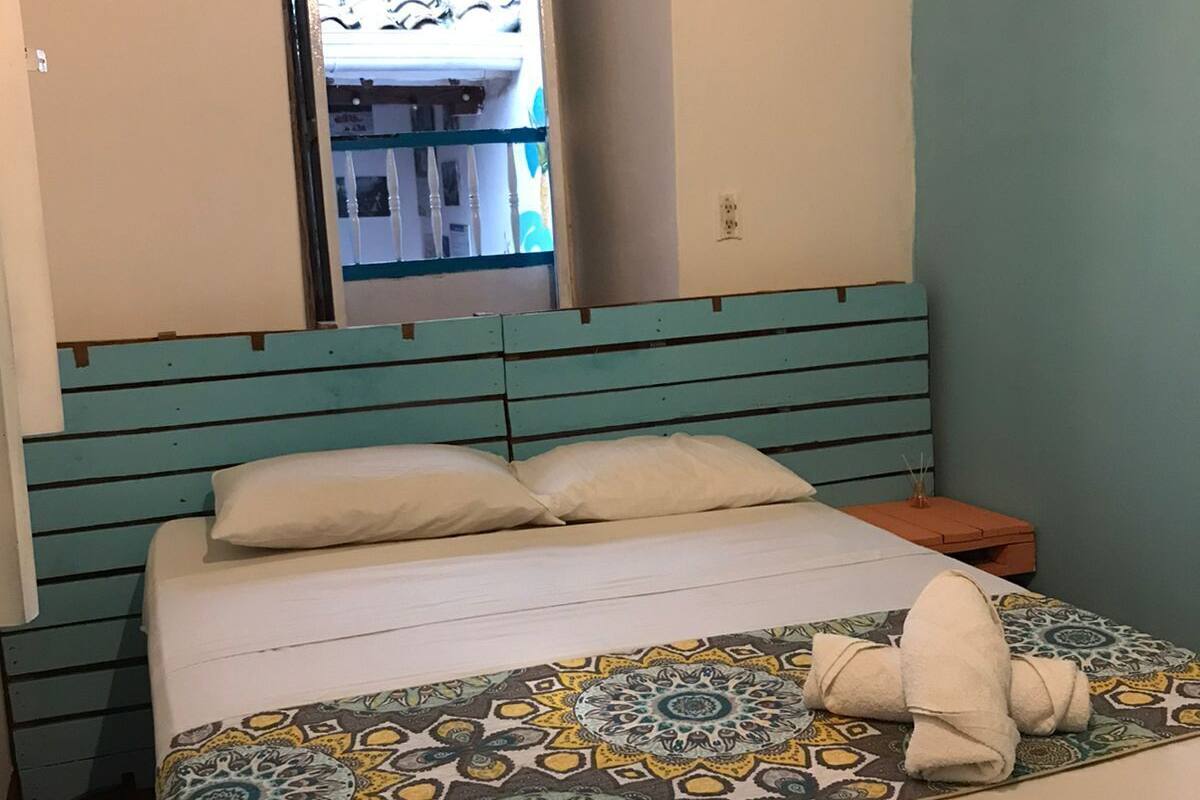 A neatly made bed with a patterned bedspread, a headboard with horizontal stripes, and a small nightstand with a lamp.