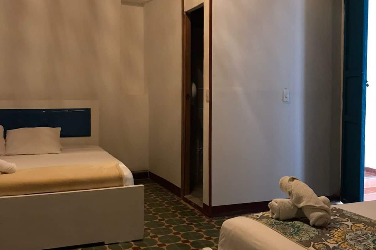 A hotel room with a bed, a wardrobe, and a patterned floor.