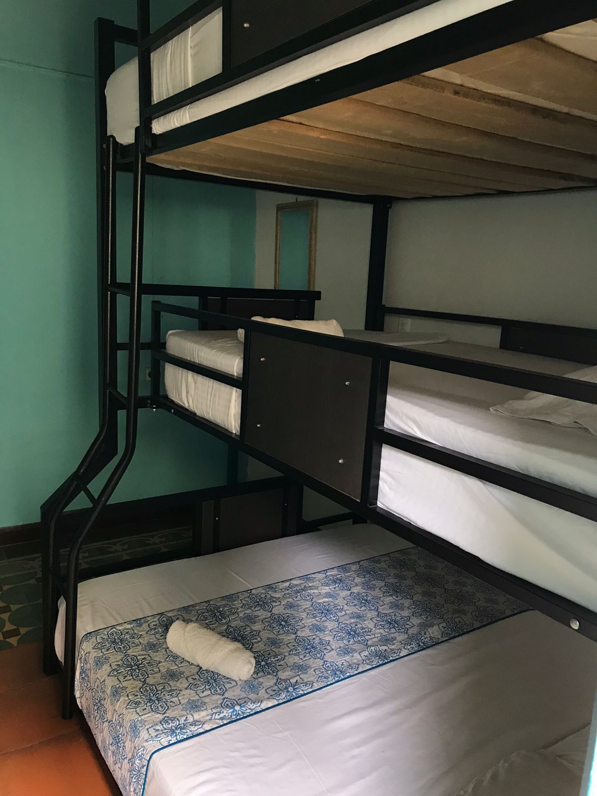 A bunk bed room with a patterned bedspread and a rolled-up towel on the lower bunk.