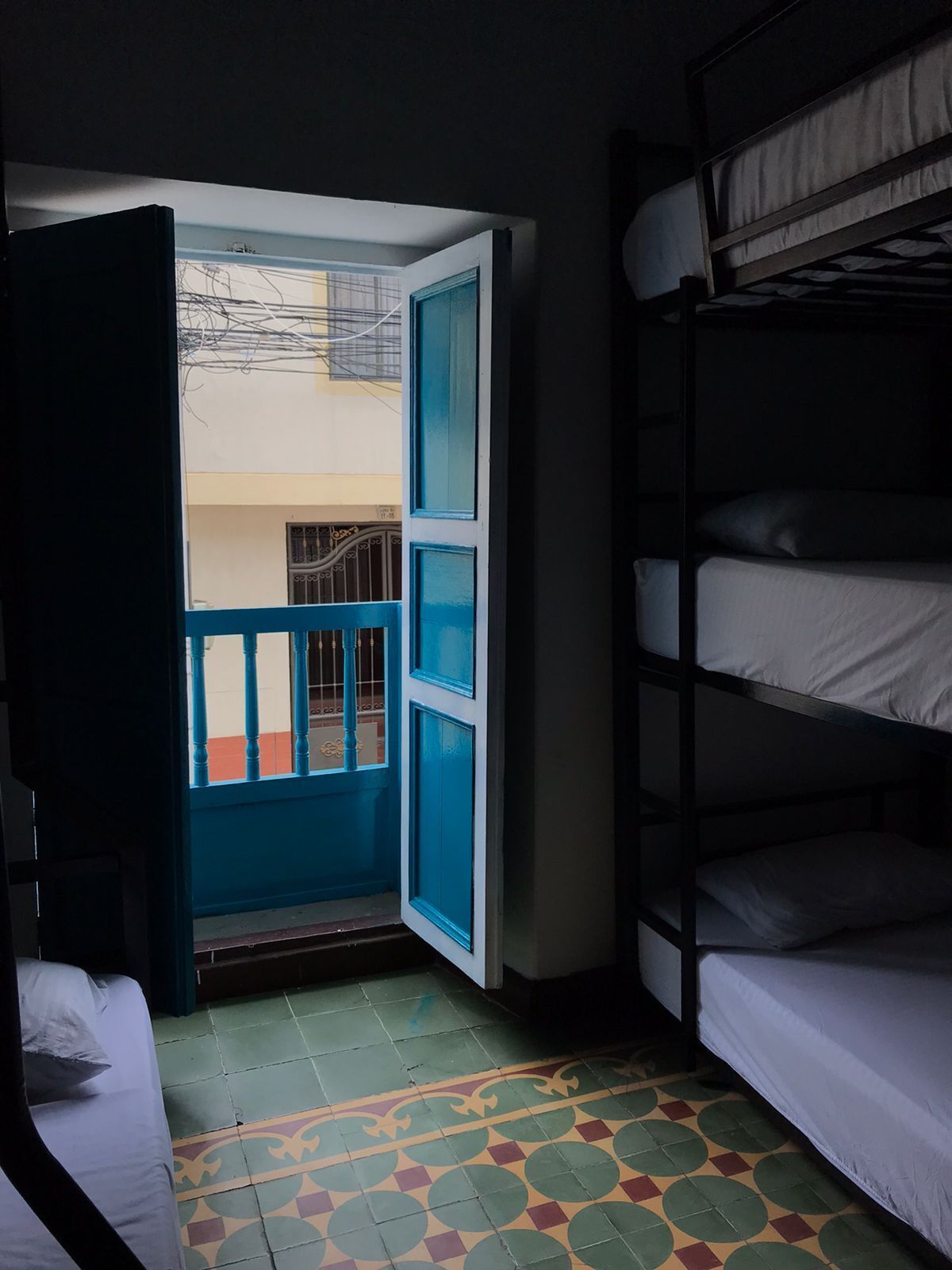 A room with bunk beds, a blue door, and a patterned floor.