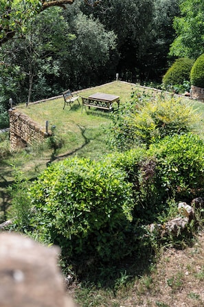A park with a wooden bench and a stone wall. - The Gîte (VITRAC)