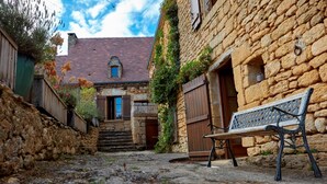 A stone building with a wooden bench in front. - The Troglodyte cave Suite (VITRAC)