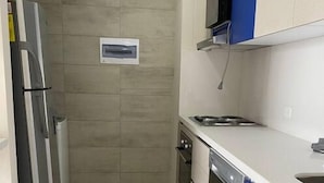 A narrow kitchen with a refrigerator, stove, and dishwasher. - Apartment in the cultural center of Bogota (Bogotá)
