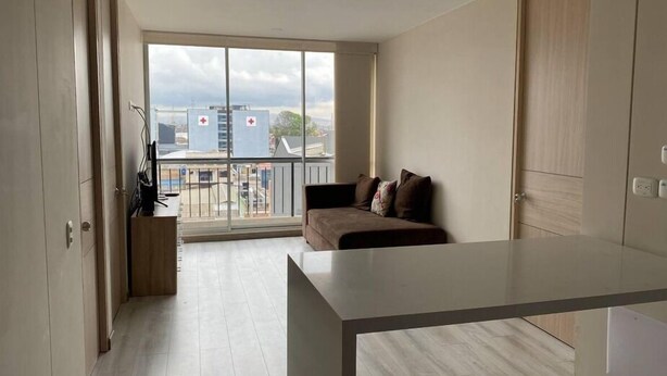 A modern apartment with a balcony, a sofa, and a minimalist kitchen area. - Apartment in the cultural center of Bogota (Bogotá)