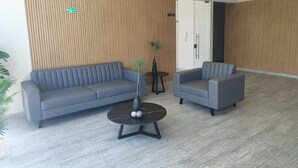 A modern waiting area with a grey sofa, a grey armchair, and a round coffee table with a vase and decorative balls. - Apartment in the cultural center of Bogota (Bogotá)