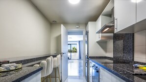 A modern kitchen with white cabinets, a granite countertop, and a stainless steel range hood. - Delfin | Pool - terrace - golf (Mijas Costa)