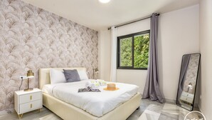 A bedroom with a bed, a nightstand, a mirror, and a window with curtains. - Delfin | Pool - terrace - golf (Mijas Costa)