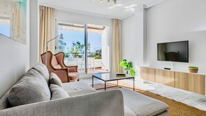 A modern living room with a sofa, armchair, coffee table, and TV.