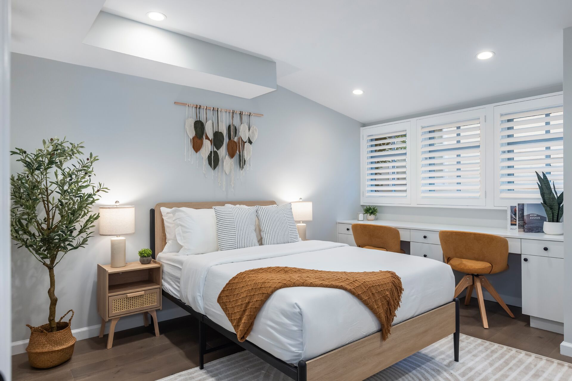 A modern bedroom with a bed, bedside tables, a desk, and a chair.
