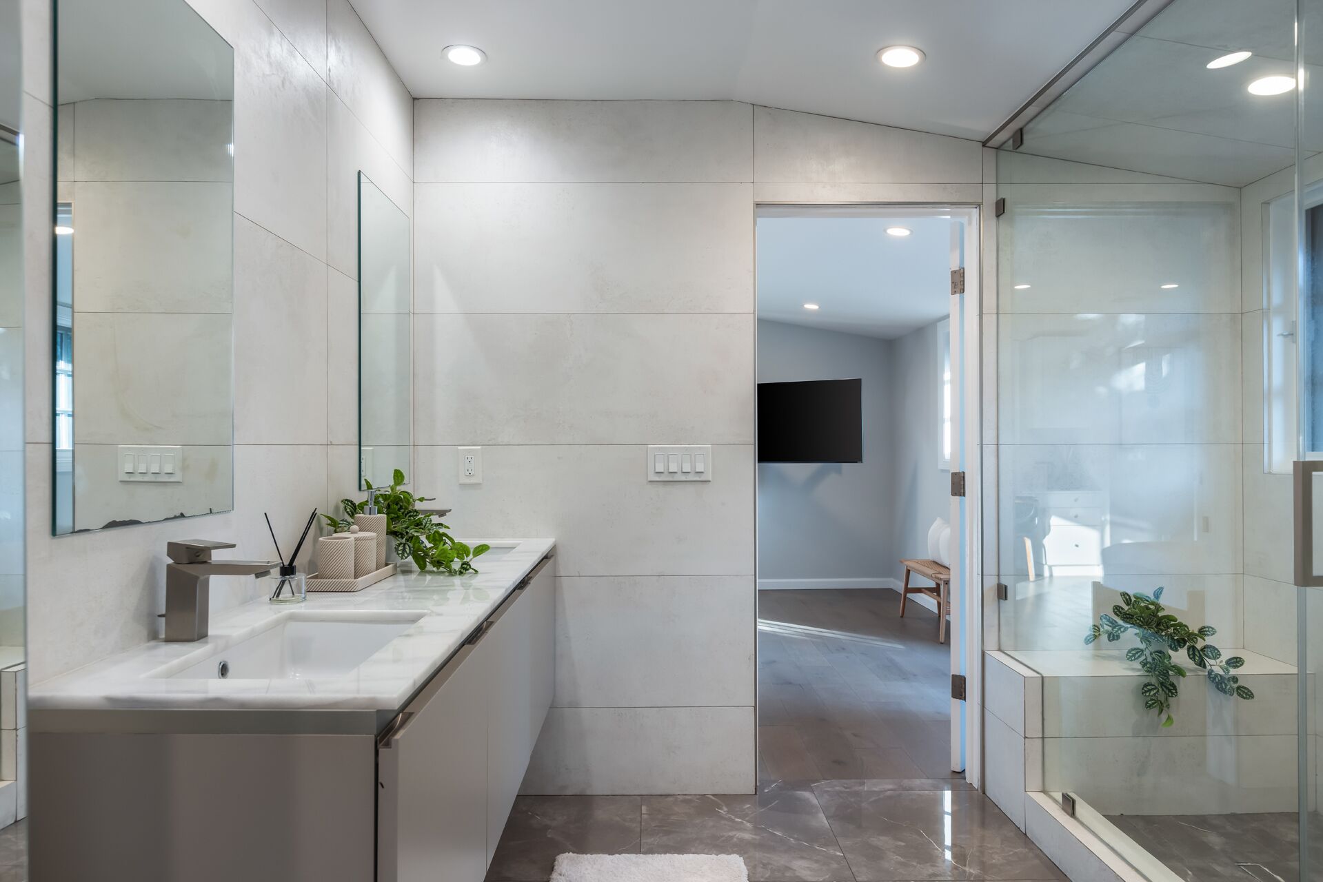 A modern bathroom with a large mirror, a sink, and a shower area.