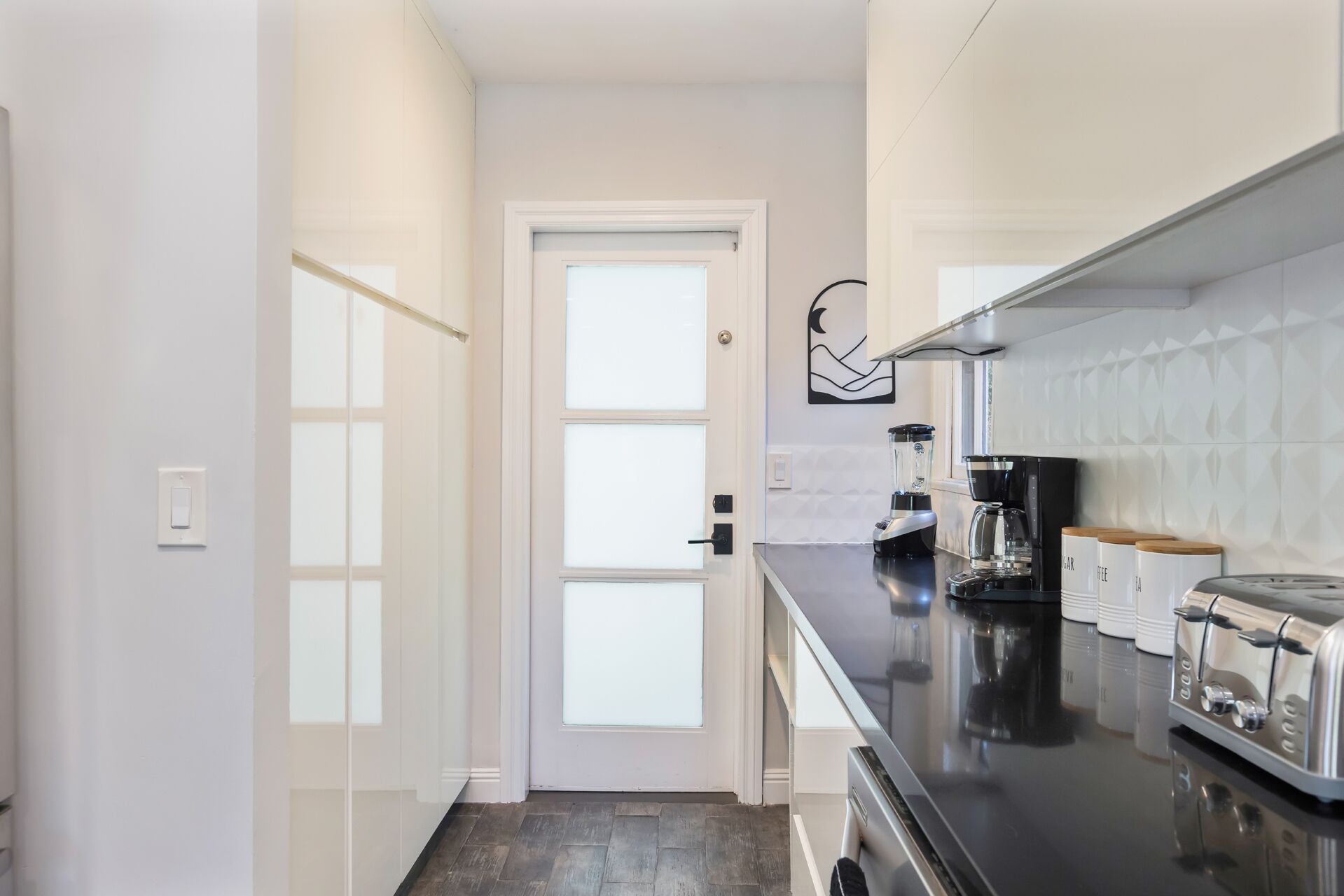 A modern kitchen with a black countertop, a coffee maker, and a blender.