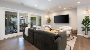 A modern living room with a grey sectional sofa, a coffee table, and a flat-screen TV mounted on the wall. - Casa Estrella by Oraklus (Los Angeles)