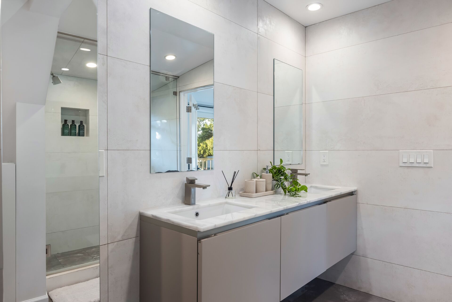 Une salle de bain moderne avec un grand miroir, un lavabo et un espace douche.