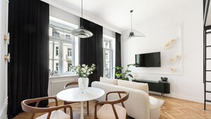 A modern living room with a white sofa, wooden chairs, a round table, and a black and white decor theme.