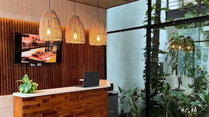 Una recepción con encimera de madera, un televisor de pantalla plana y lámparas colgantes.