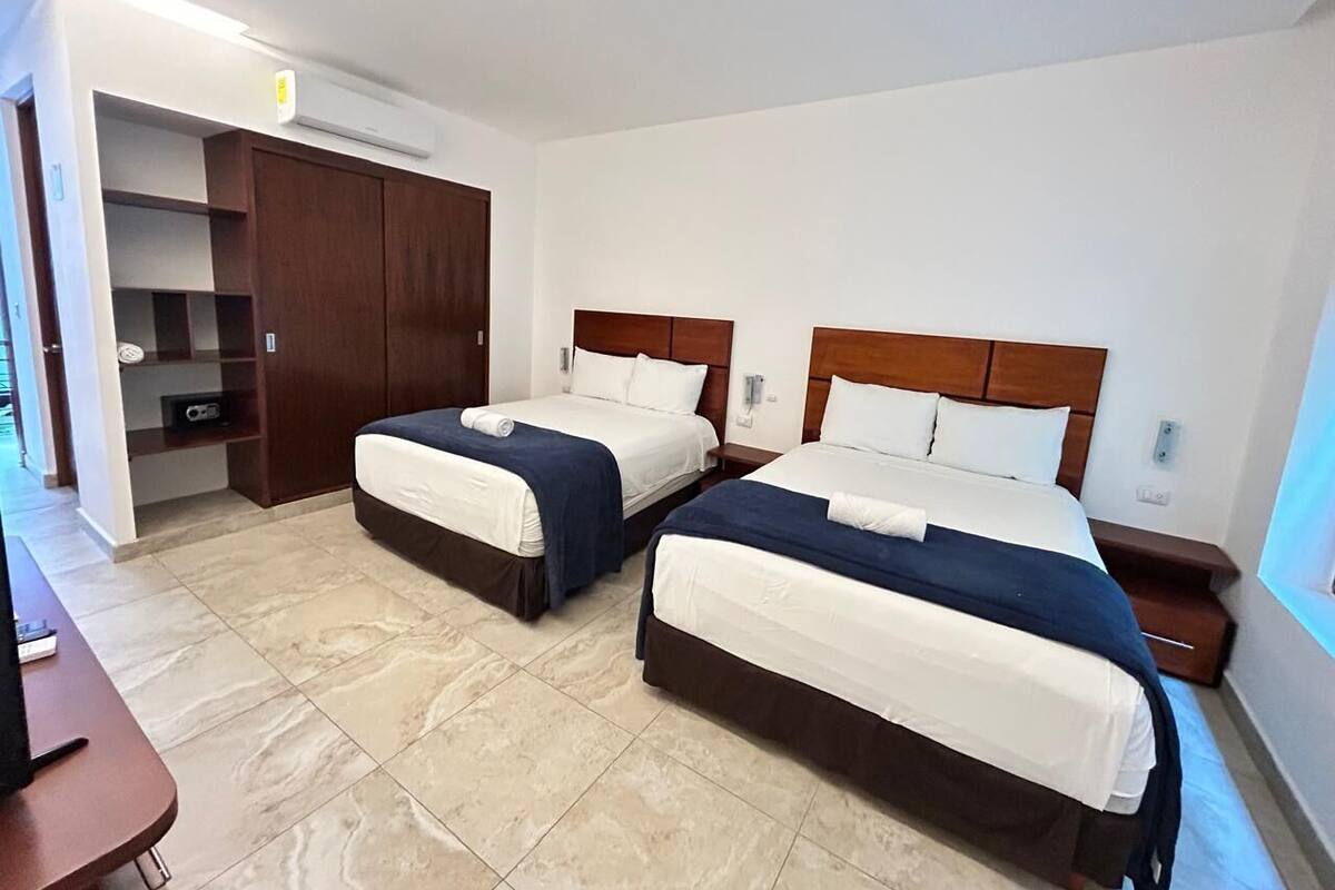 A hotel room with two beds, a wardrobe, and a desk.