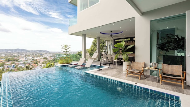 Une maison moderne dotée d’une piscine à débordement sur le toit, offrant une vue panoramique sur la ville.