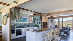 Een moderne keuken met een groot eiland, barstoelen en uitzicht op de omgeving.