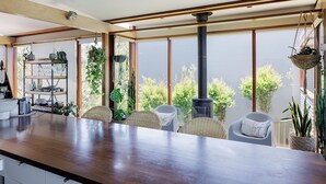 Een moderne keuken met een houten aanrecht, rieten stoelen en een groot raam met uitzicht op groen.