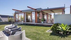 Een modern huis met een terras, buitenmeubels en een verzorgd gazon.
