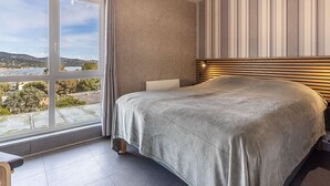 Una camera da letto con un letto grande, vista su un lago e una parete a righe.