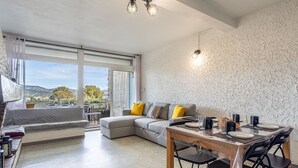 Un soggiorno moderno con divano, tavolo da pranzo e sedie. Grande finestra con vista sull'esterno.