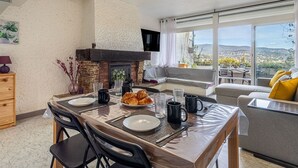 Zona pranzo con tavolo apparecchiato per due, camino e vista sulla città e sulle colline.
