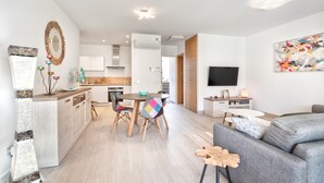 Un apartament modern amb cuina, zona de menjador i saló.