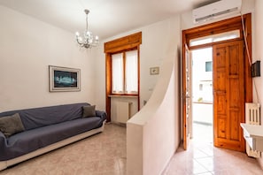 A living room with a sofa, a chandelier, a framed picture, a wooden door, and a radiator. - Casa Torre San Giovanni Near the Sea, Ugento, Italy (Ugento)