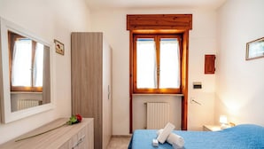 Un dormitorio con cama, cómoda, radiador y ventana.