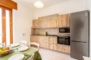 Une cuisine moderne avec des meubles en bois, un réfrigérateur en acier inoxydable, un four à micro-ondes et une cuisiniÚre à gaz.