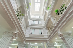 Un interior imponente con columnas ornamentadas, un tragaluz central y barandillas de hierro decorativo.