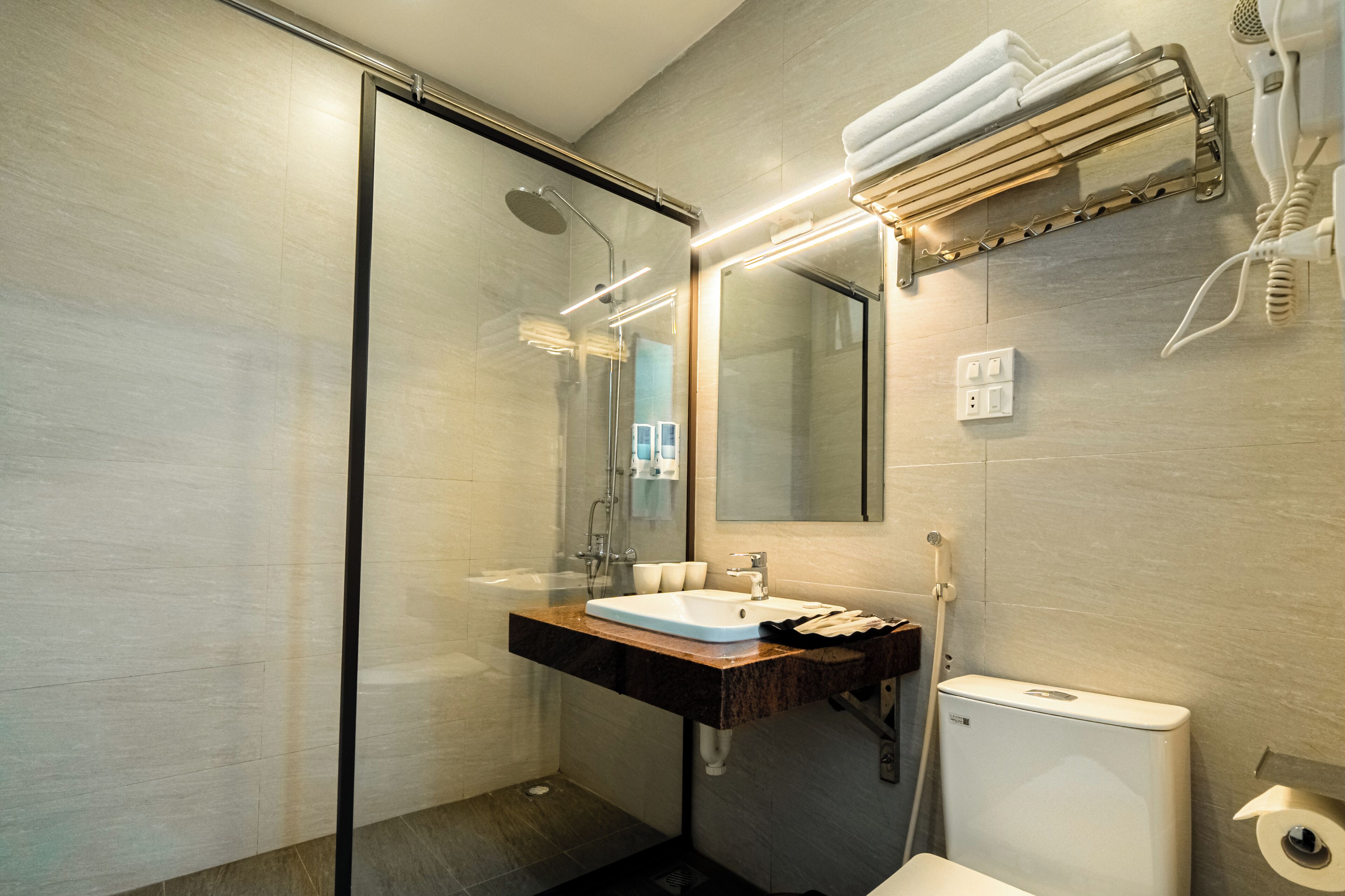 Ein modernes Badezimmer mit einer Duschkabine aus Glas, einem Waschbecken mit Marmorplatte und einer Toilette.