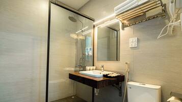 Ein modernes Badezimmer mit einer Duschkabine aus Glas, einem Waschbecken mit Marmorplatte und einer Toilette.