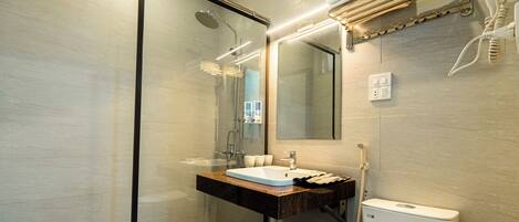 A modern bathroom with a glass shower enclosure, a sink with a marble countertop, and a toilet.