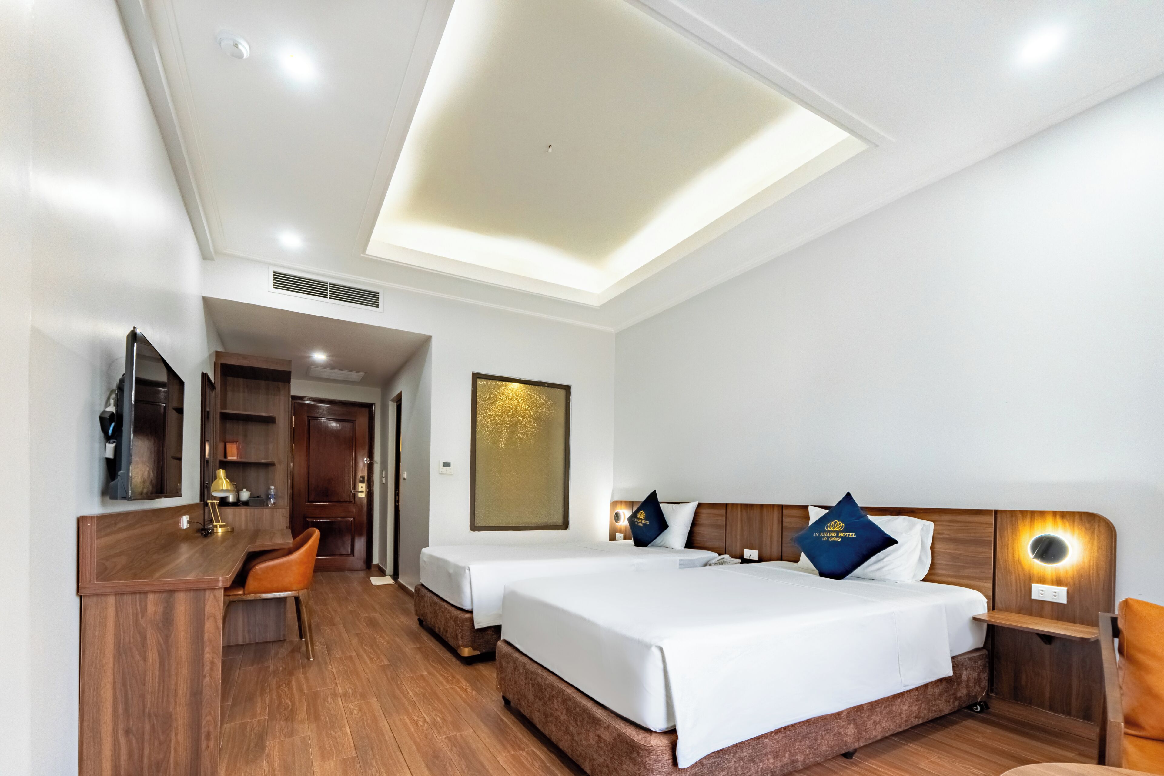 A hotel room with a bed, a desk, a chair, and a TV.