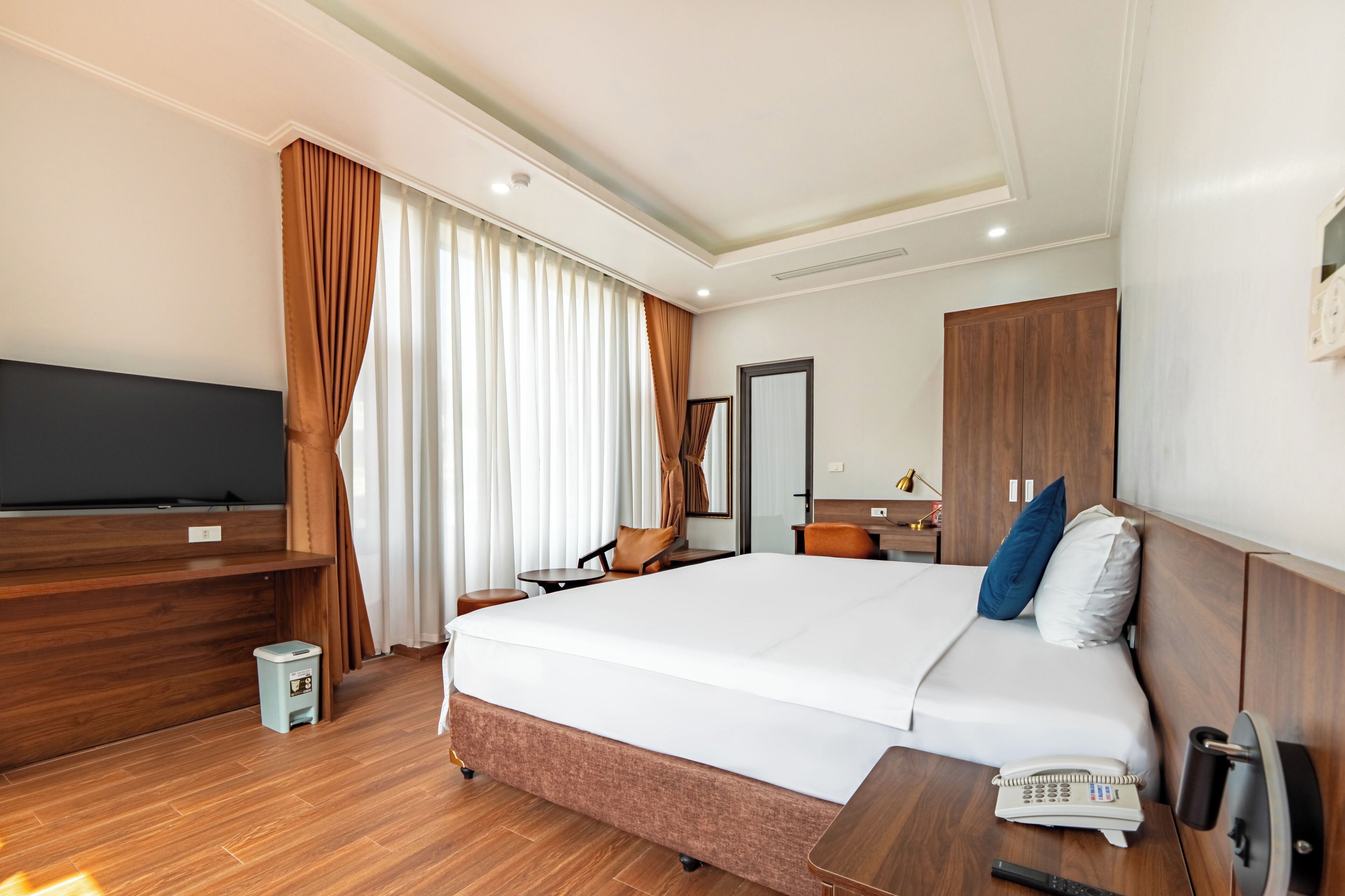 Ein Hotelzimmer mit Bett, Schreibtisch, Fernseher, Spiegel und Kleiderschrank.