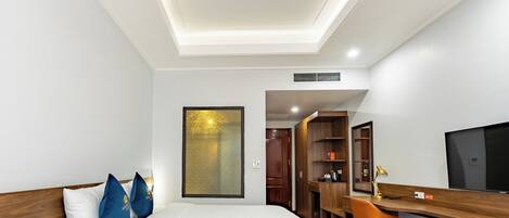 Ein Hotelzimmer mit Bett, Schreibtisch, Fernseher und Kleiderschrank.